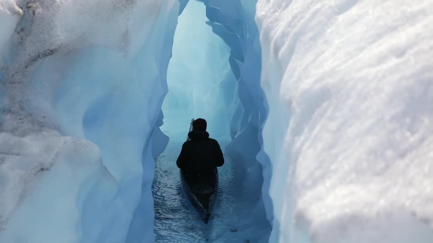 A person kayaks through an icy tunnel