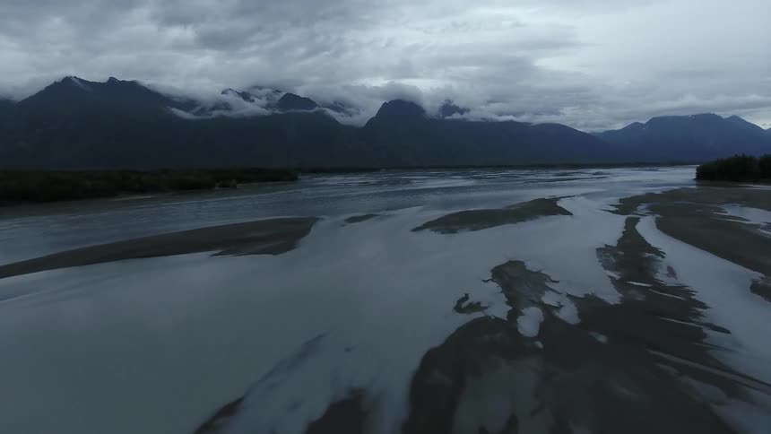 Clouds float over mountains near a river