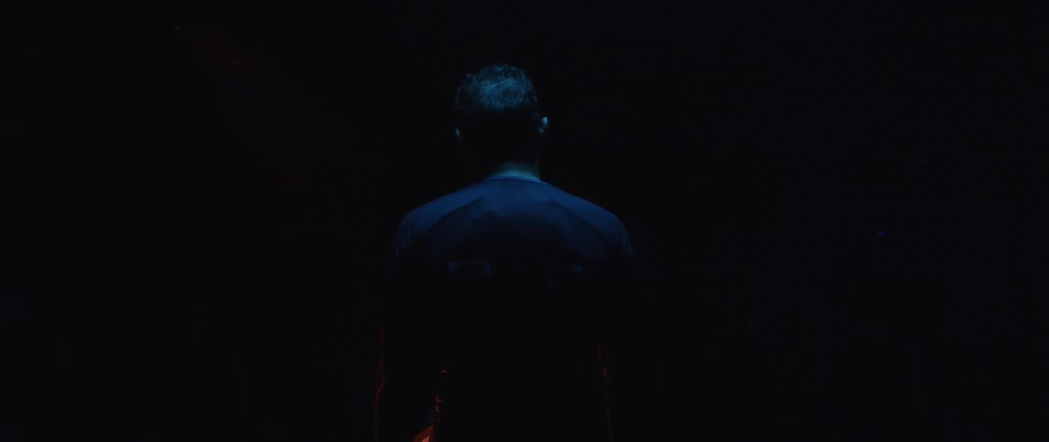 A person leans forward in the dark