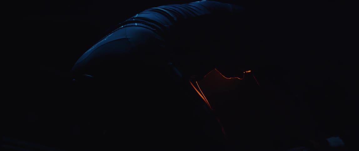 Silhouette of a man wearing a cycling jersey and shorts exercising on a stationary bike in a dark room