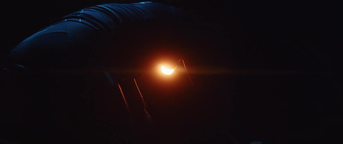 Man exercising on a stationary bike in a dark room illuminated only by an orange led light
