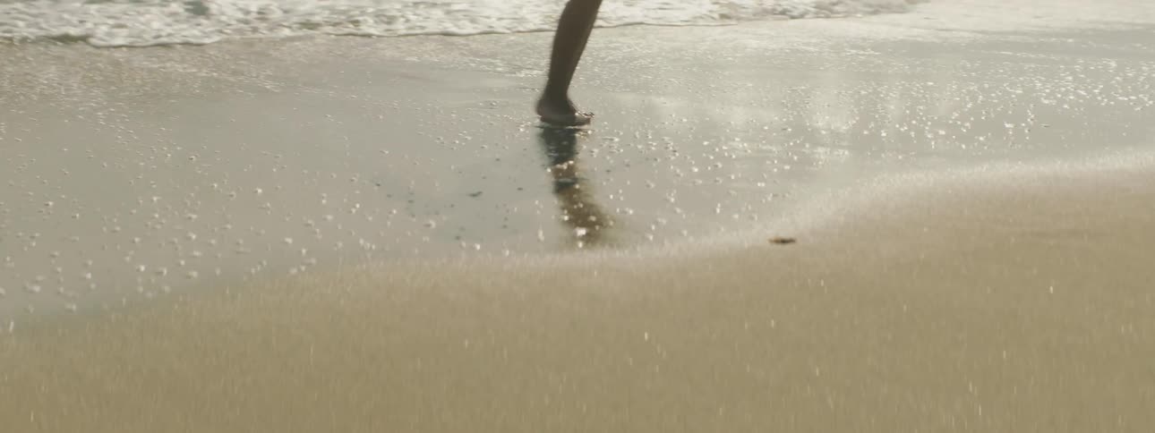 A person walking on a sandy beach with waves
