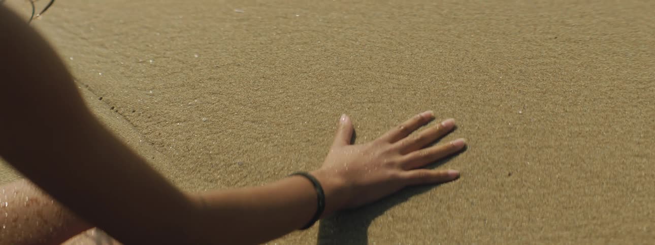 A woman puts a hand print in the sand