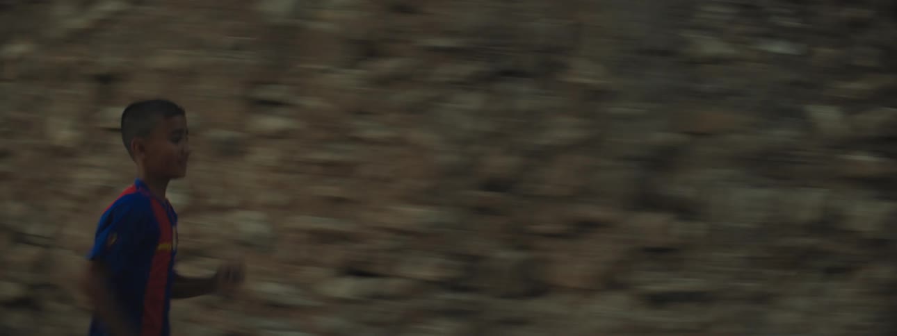 A young boy runs past rubble in a third world country