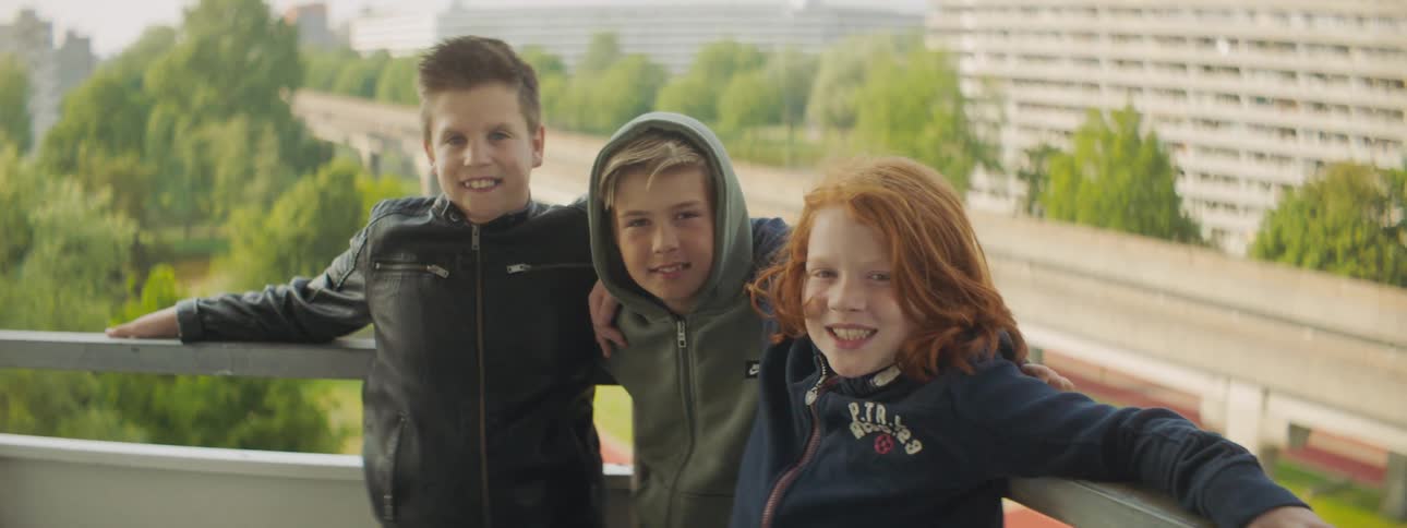 Three children stand together smiling