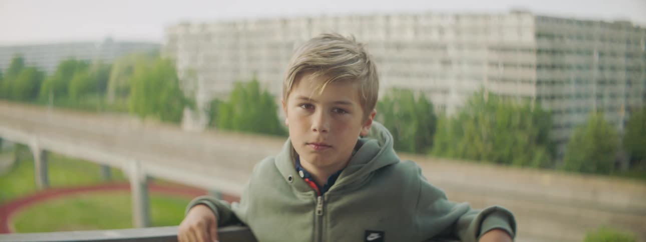 A boy is leaning against the railing outside
