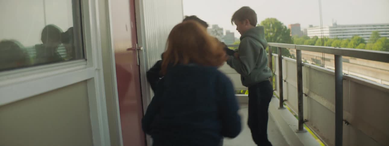 Two boys take a book from another boy on a balcony and push him down