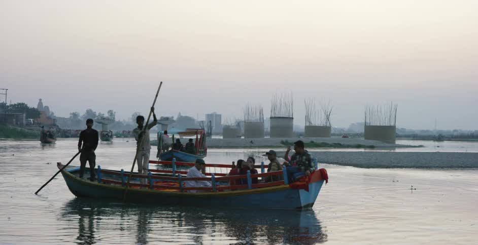 People ride in a boat being paddled with a large stick