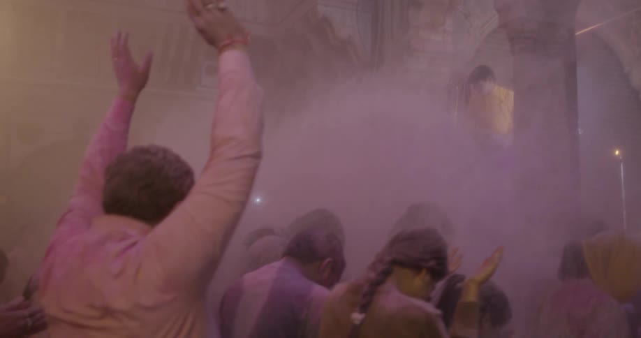 A man throws pink powder on a crowd