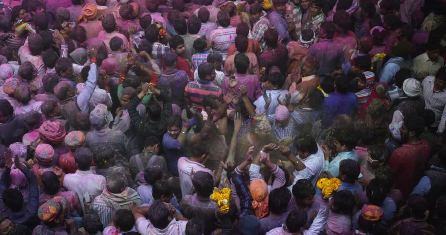 A jubilant Audience throws multi-colored powder on each other