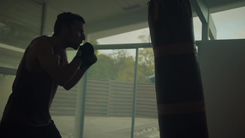 A man repeatedly hits a punching bag