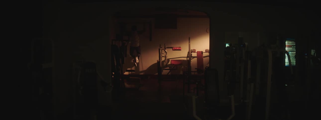 A man jumps up grabs a bar and does several pull ups in his workout room