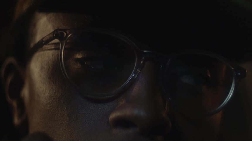 Man wearing glasses closes his eyes in dark area