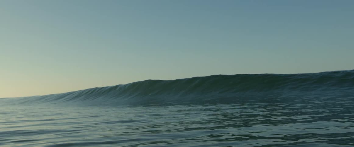 A tall wave falls into the ocean