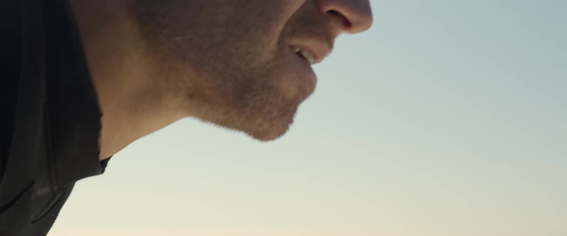 The bottom part of a mans face is seen above the ocean as it moves