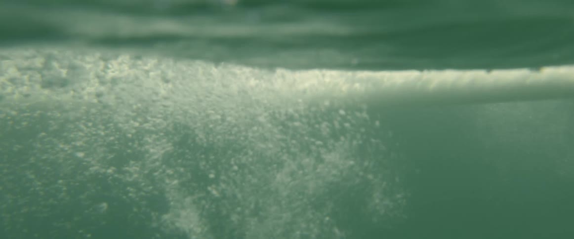 Surfers hand moves through water while surfer paddles on board