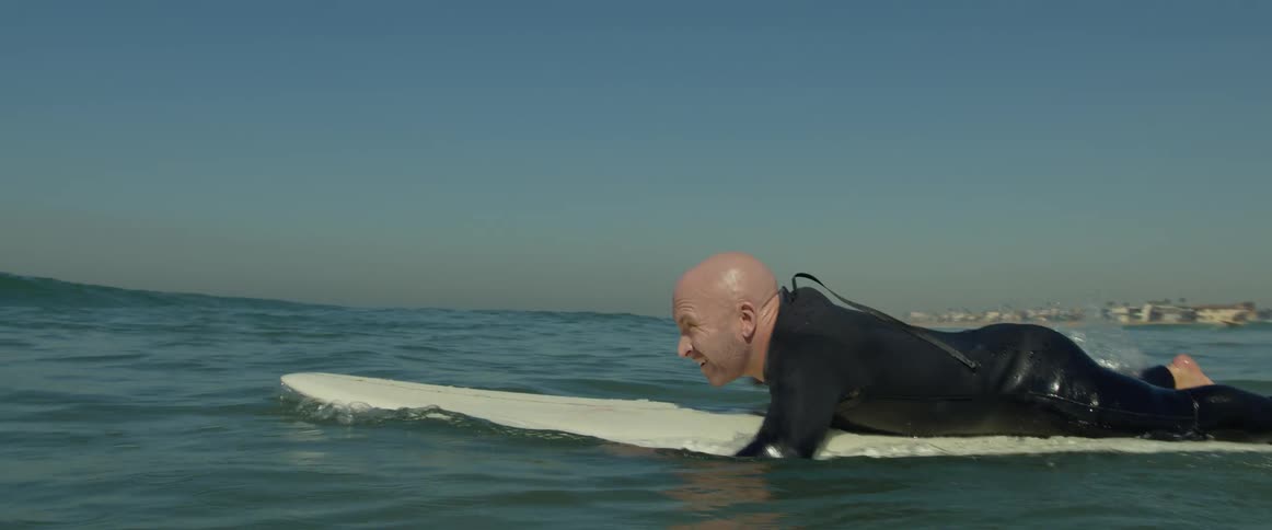 A man paddling out on a surfboard