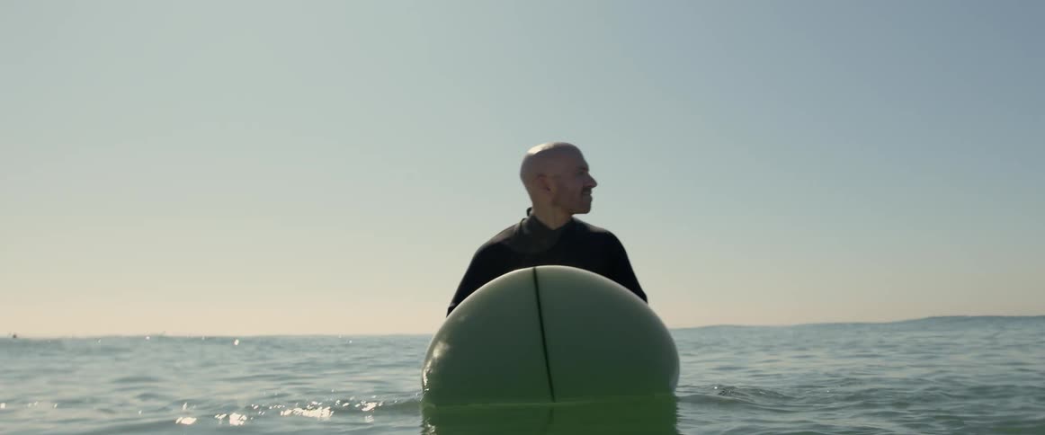 A man is sitting on a surfboard waiting for a wave