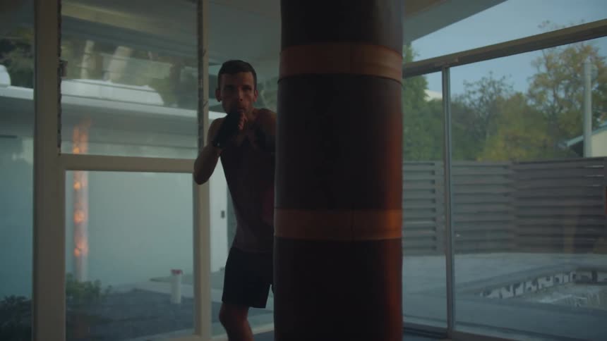 A man is practicing punches using a punching bag