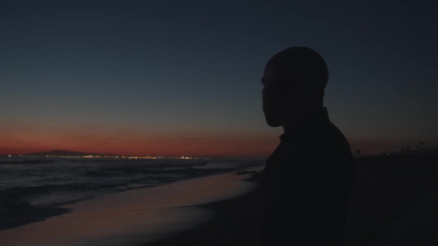 A man is standing by the beach during sunset