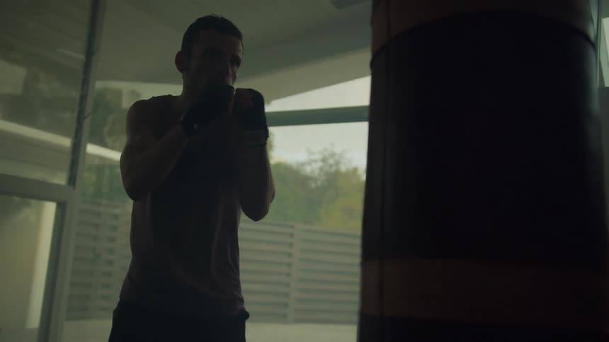 A man is punching a hanging bag with gloved hands