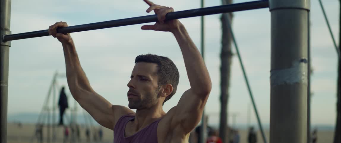 A man prepares to exercise on equipment in a public park on a beach during the day