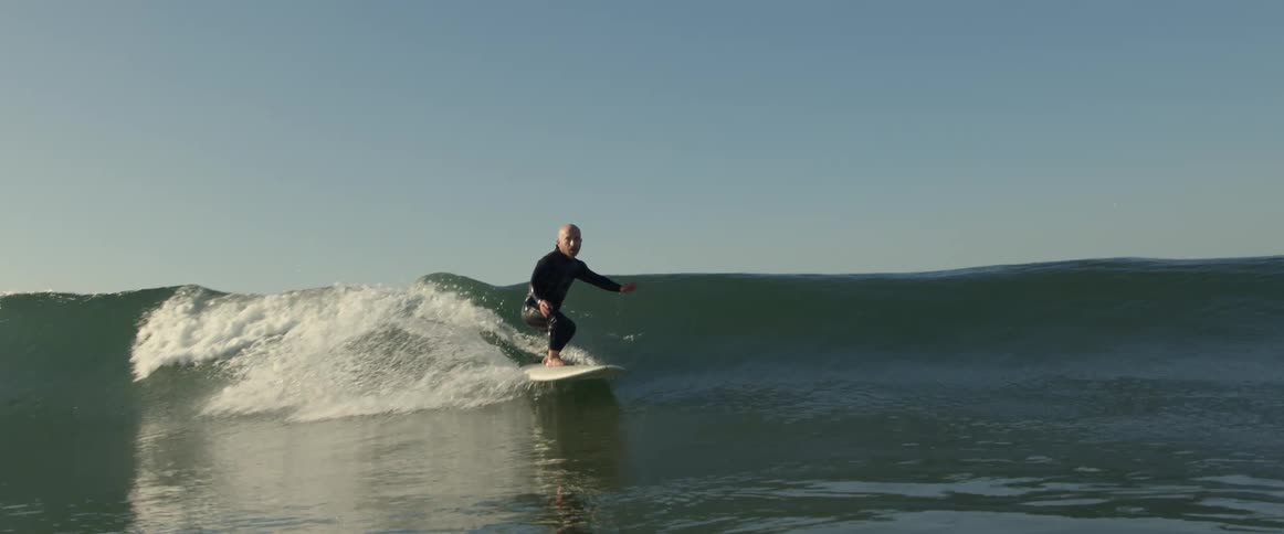 A man rides a surfboard on a large wave