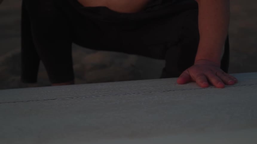 A man is polishing his surfboard