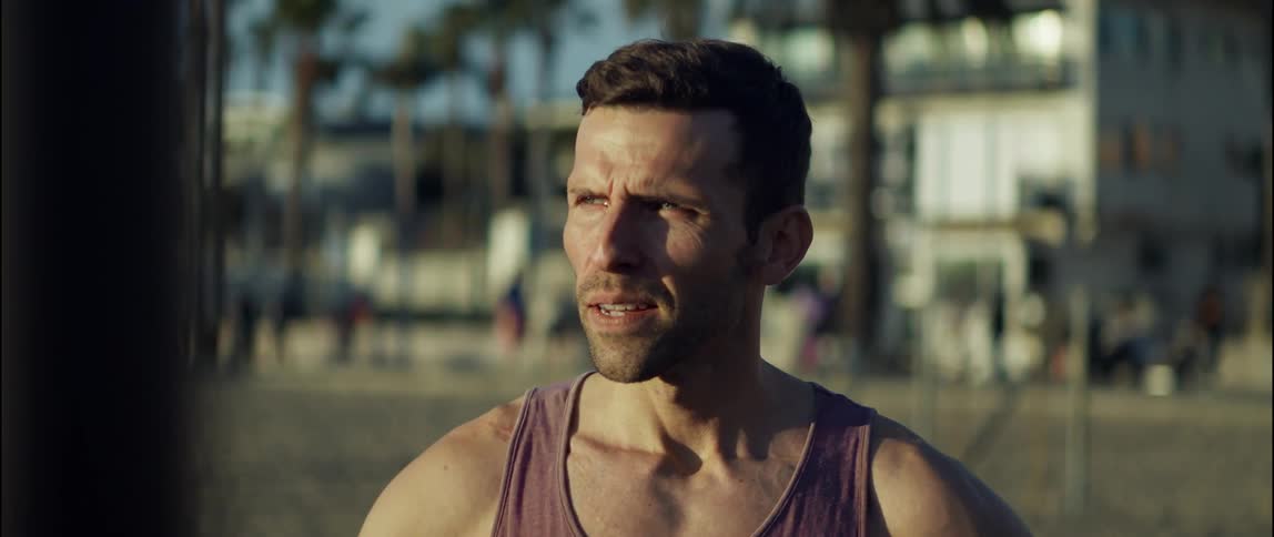 A concerned looking man in a tank top outside on a sunny day