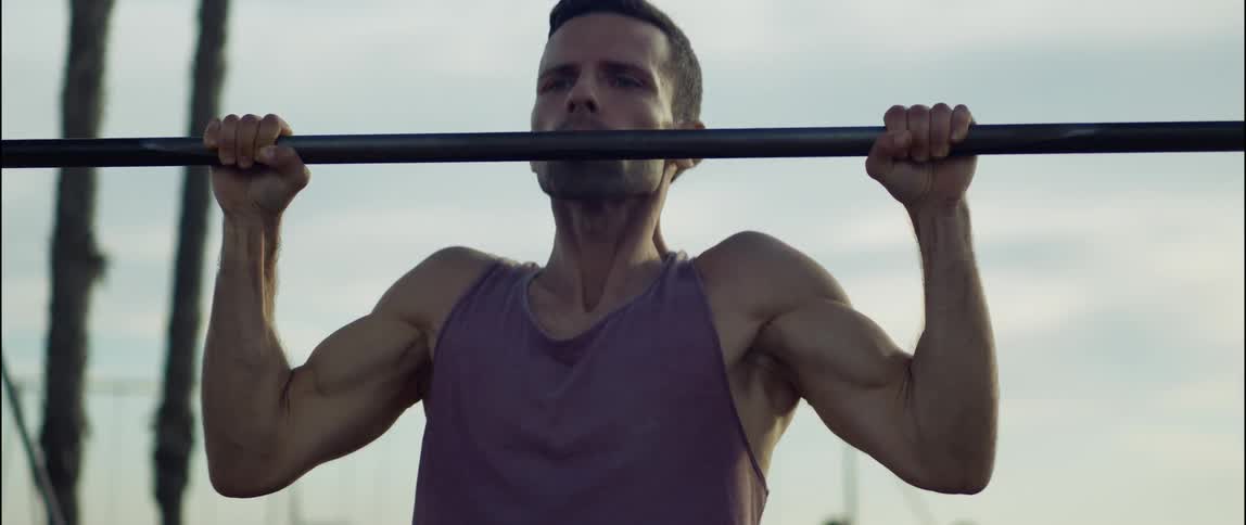 A man is doing pullups in a park