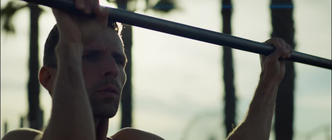 A young man is working out outside in the middle of the day