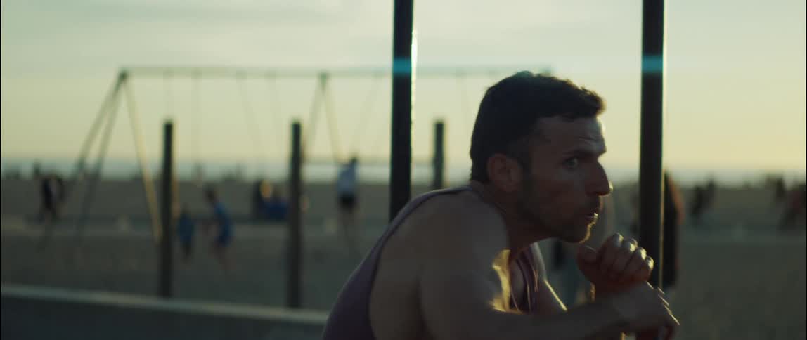 A man is shadowboxing on a playground while people swing