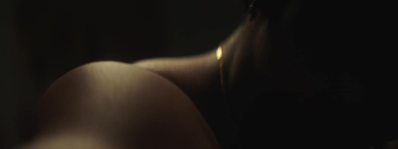 A young black man is sitting down in the dark