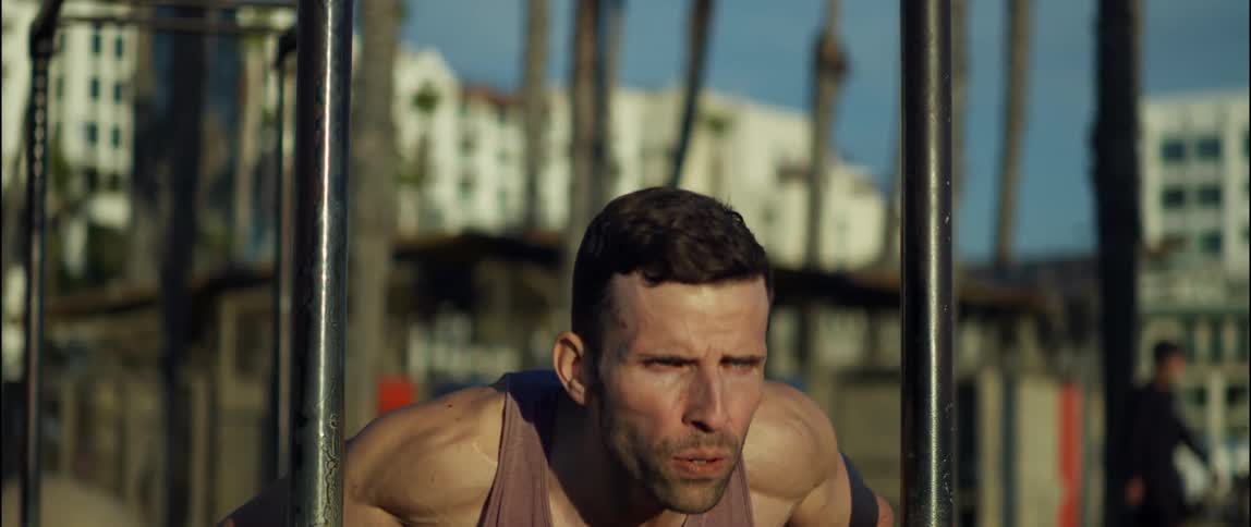 A man does pushups outside in a city during the day