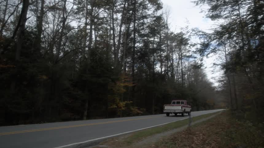 A few cars are driving down the road next to some trees