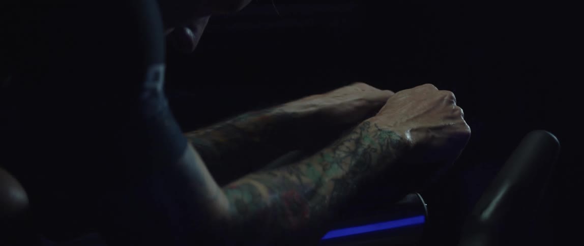A tattoo covered man prepares to ride an exercise bike
