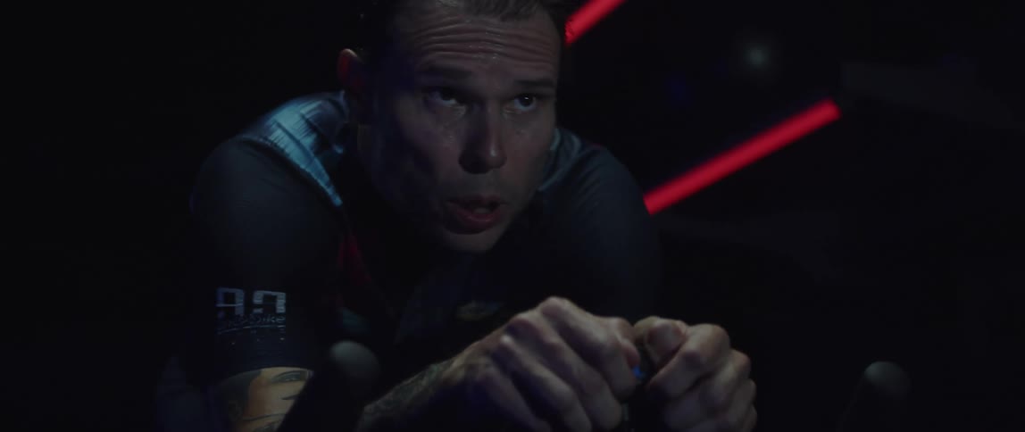 A man breathing heavily and sweating while riding a stationary bike