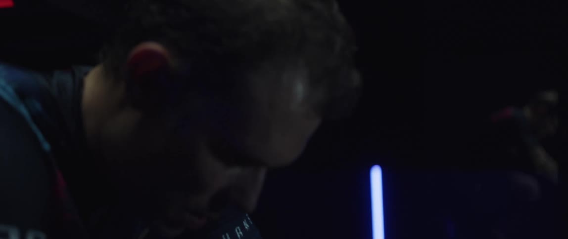 A man sweating while riding a stationary bike in a dark room