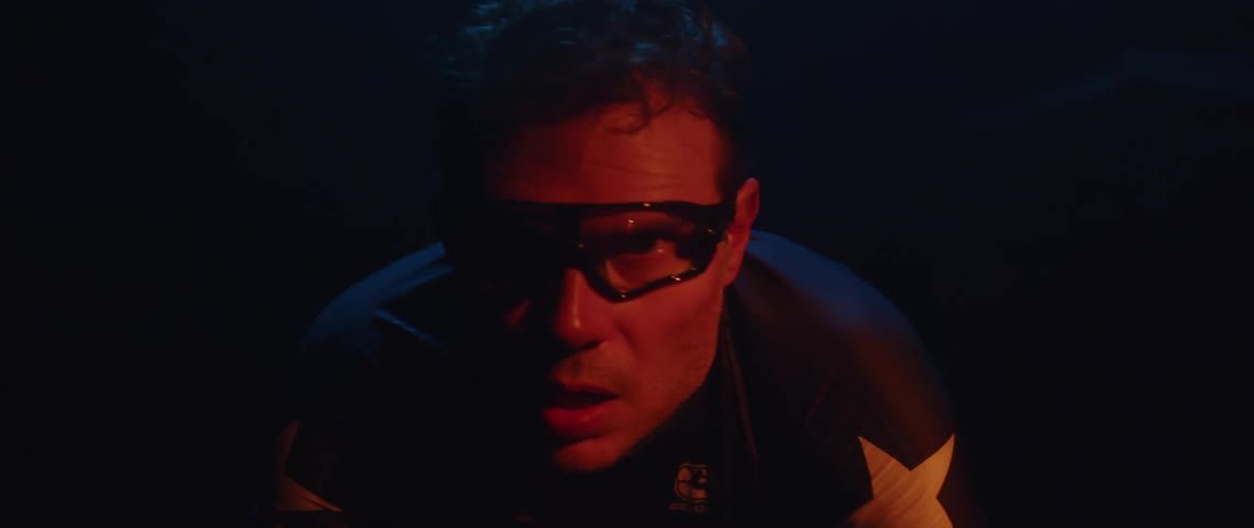 Man pedaling on a static bicycle inside a dimly lit room against a dark background