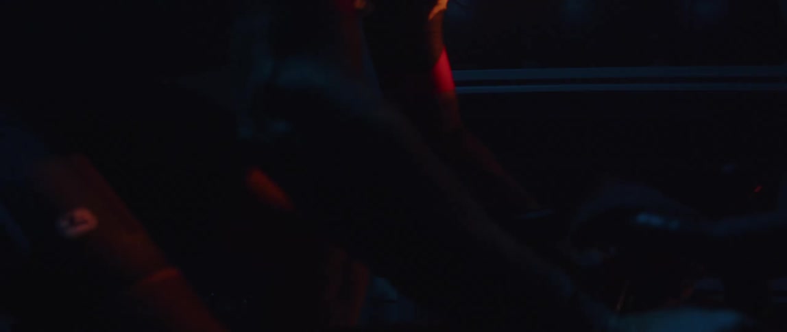 Man wearing sunglasses pedaling a static bicycle inside a dimly lit room