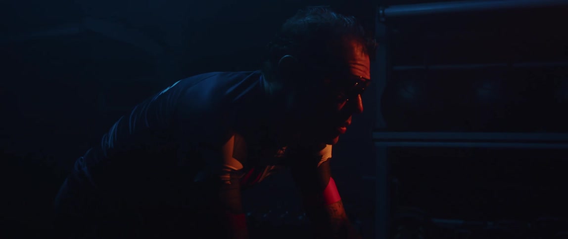 Determined and sweaty male cyclist with jersey shirt and tattoos rides exercise bike