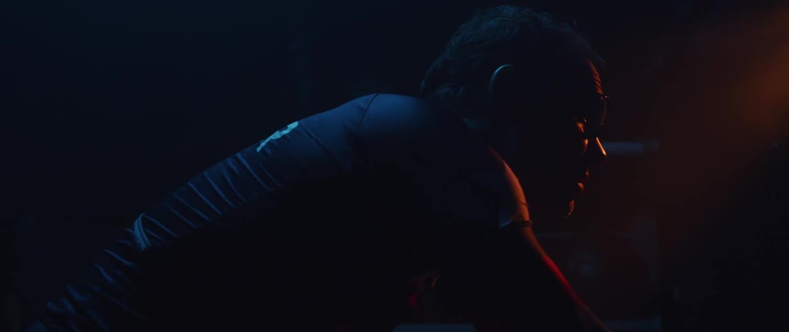 A man is leaning forward in the dark room