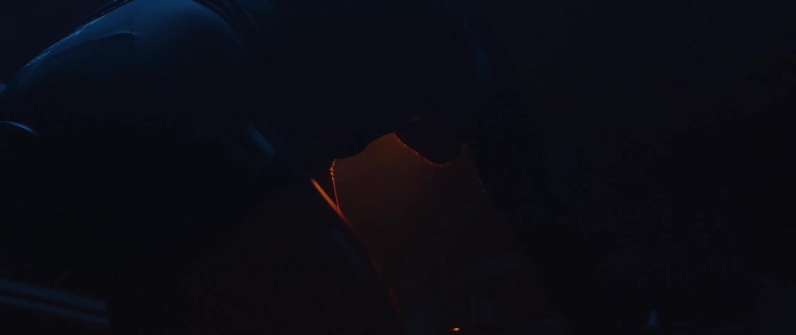 A man is in a dark room riding an exercise bike