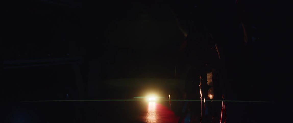 A man pedals on an exercise bike in a dimly lit room