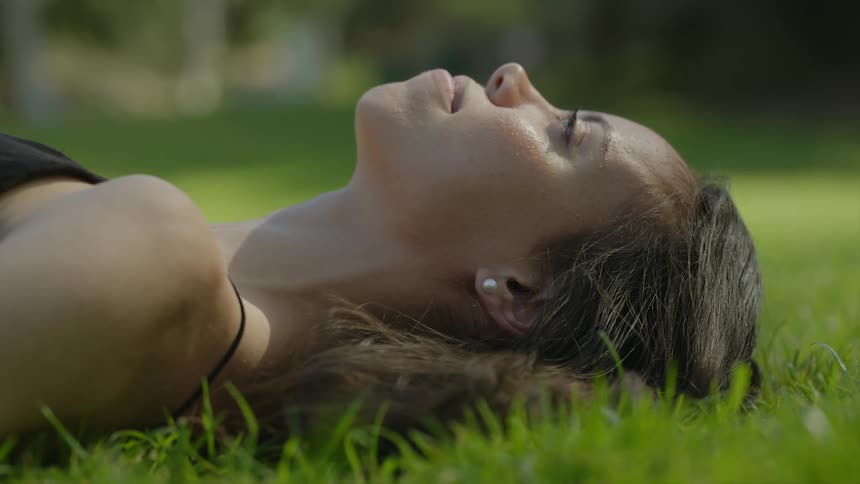 Smiling woman lies on lawn