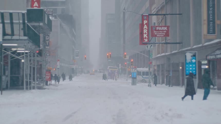 People walk across a snowy city street