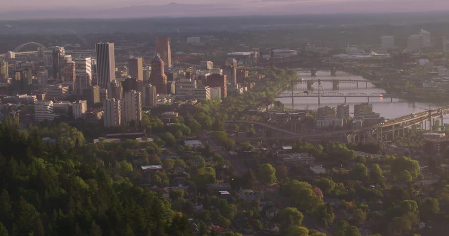 An aerial view of a river running through a city with high rise office buildings and cars driving