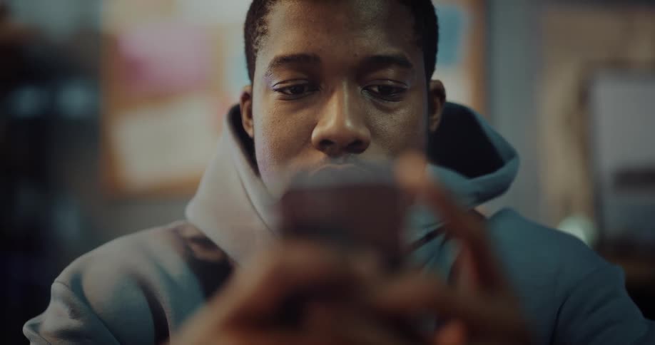 Young man sitting on a room at hme texting on his phone