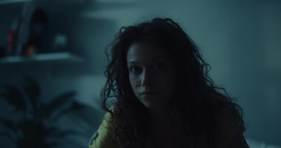 A woman sits up in bed staring forward