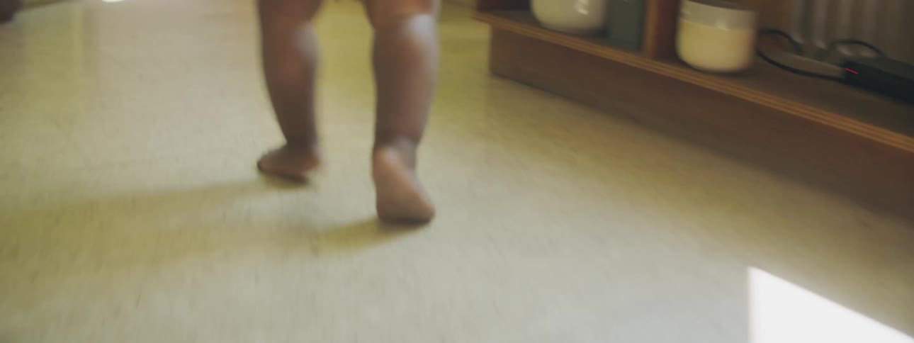 A baby wobbly runs toward the kitchen in their home